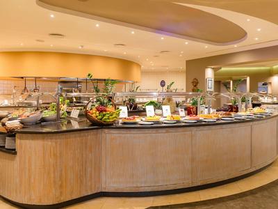 Buffet en hotel moderno con variedad de ensaladas y verduras en ambiente cálido.