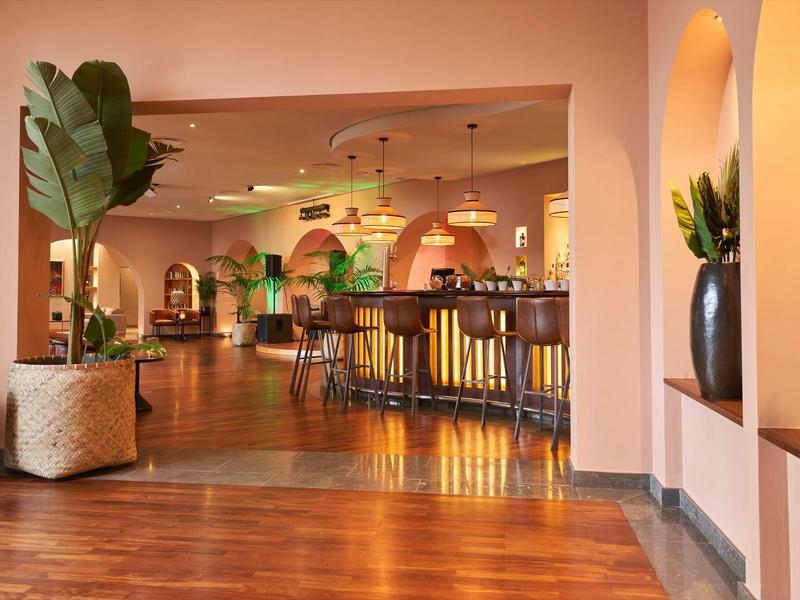 Eleganter Hotelbarbereich mit warmem Licht, Pflanzen und stilvollen Sitzgelegenheiten.