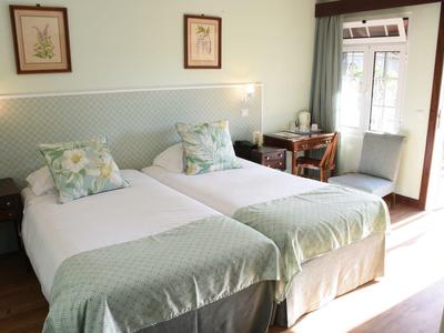 Gemütliches Schlafzimmer mit zwei Einzelbetten, hellen Holzmöbeln und Zugang zu Gartenbereich.