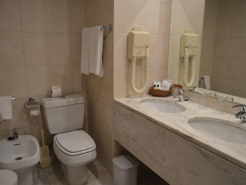 Sauberes Badezimmer mit WC, Bidet, Handtüchern, Doppelwaschbecken und Spiegelwand.