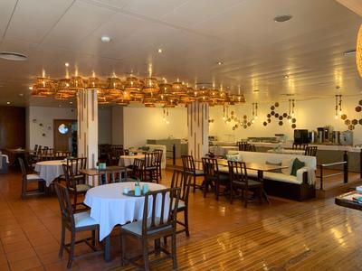 Ristorante elegante dell'hotel con pavimento in legno e lampadari eleganti sopra tavoli con tovaglie bianche.