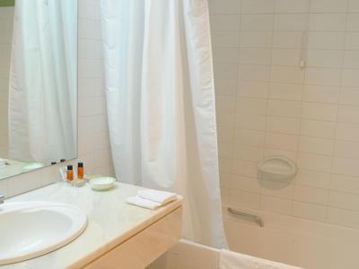 Bagno luminoso con tenda bianca, lavandino e articoli da bagno.