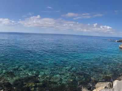 Mare turchese limpido con costa rocciosa e cielo azzurro in una giornata di sole.