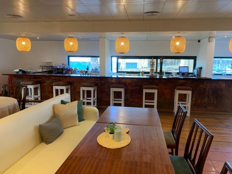 Sala da pranzo moderna con tavoli in legno, sedie e una panca imbottita in un hotel.