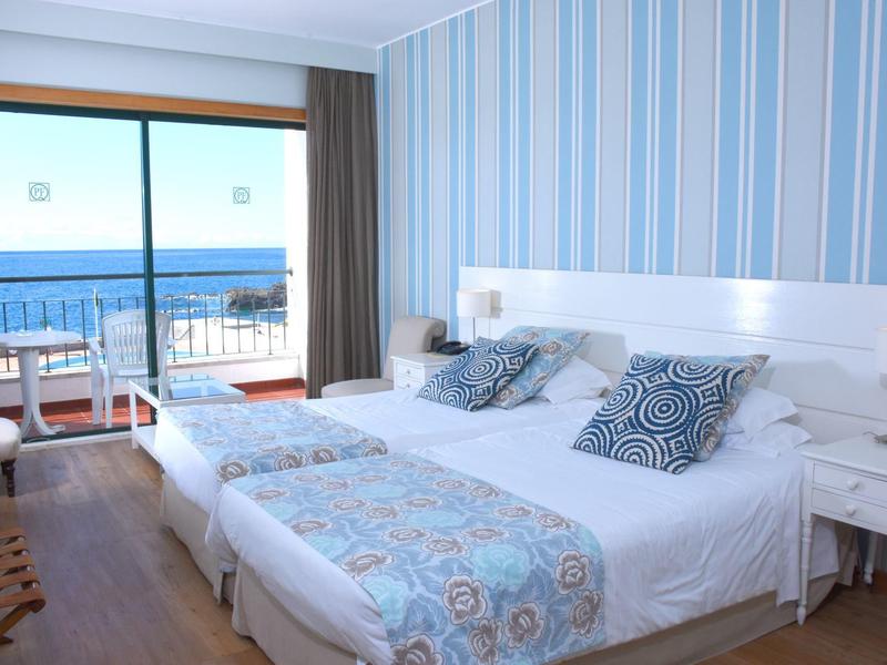 Camera d'hotel luminosa con letto matrimoniale, balcone e vista mare.