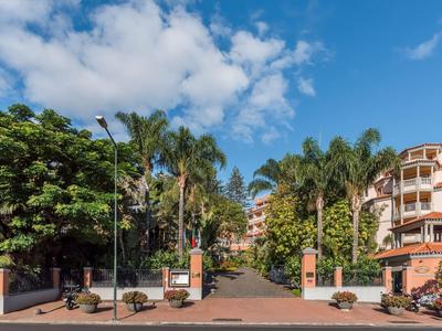Ingresso dell'hotel con palme e muri di mattoni rossi sotto un cielo azzurro.