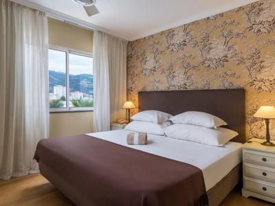 Camera d'hotel accogliente con letto matrimoniale, comodini e finestre con vista sulle montagne.