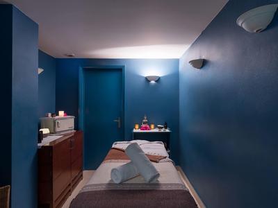 Stanza per massaggi tranquilla con pareti blu, lettino da trattamento e asciugamani.