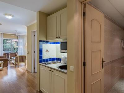 Vista di una camera d'hotel con soggiorno, angolo cottura e corridoio del bagno.