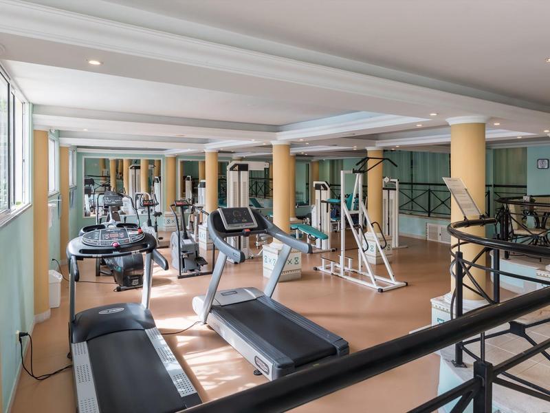 Palestra luminosa con tapis roulant, macchine per allenamento e ampie finestre.