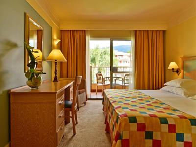 Camera d'hotel accogliente con letto grande e balcone con vista sulle montagne.