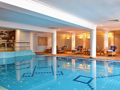 Piscina coperta con pavimento piastrellato blu e aree relax in un hotel