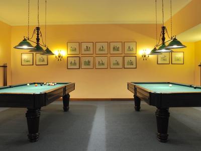 Due tavoli da biliardo in una stanza ben illuminata con pareti gialle e diverse immagini.