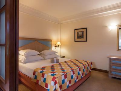 Camera d'hotel accogliente con letto matrimoniale, copriletto colorato e illuminazione calda.