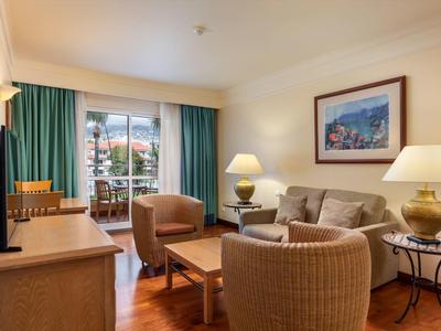 Hotel con grande piscina all'aperto, giardino e vista sulla costa al tramonto.