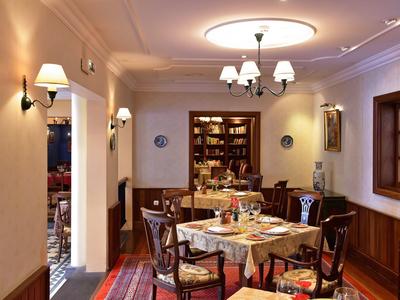 Ristorante accogliente con tavoli apparecchiati, mobili in legno e libreria a parete.