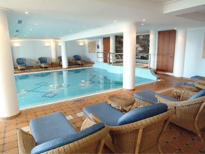 Piscina coperta con lettini e pavimento piastrellato in un hotel.