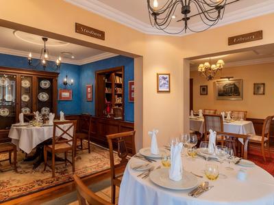 Ristorante elegante con tavoli apparecchiati, sedie di legno e arredamento tradizionale.