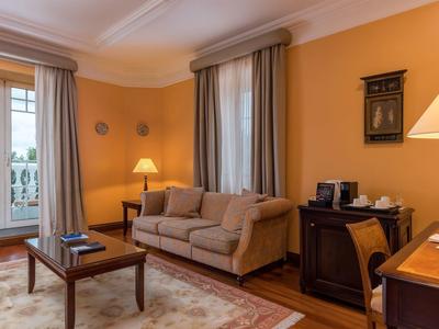 Accogliente soggiorno con divano, tavolo in legno, tappeto e pareti gialle in una camera d'hotel.