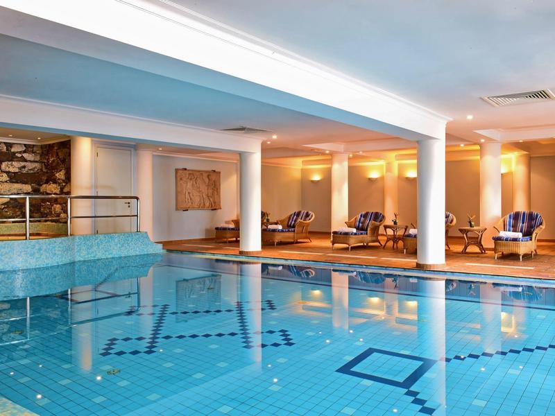 Piscina coperta con pavimento piastrellato blu e aree relax in un hotel