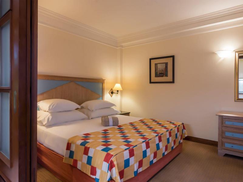 Camera d'hotel accogliente con letto matrimoniale, copriletto colorato e illuminazione calda.