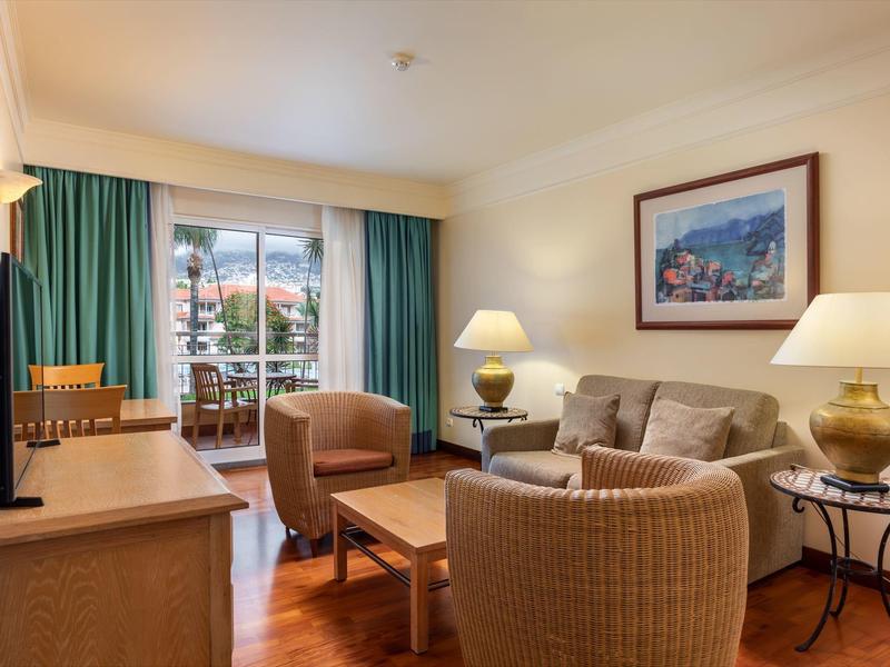 Hotel con grande piscina all'aperto, giardino e vista sulla costa al tramonto.