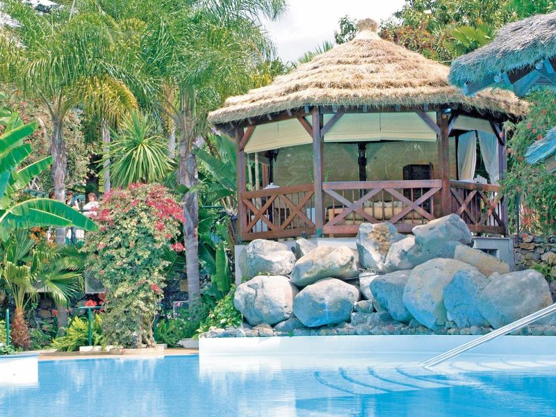 Area piscina rilassante con capanna in legno e vegetazione tropicale