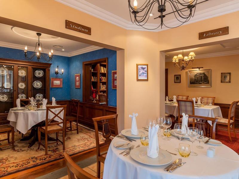 Ristorante elegante con tavoli apparecchiati, sedie di legno e arredamento tradizionale.