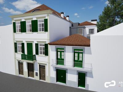 Traditionelles zweistöckiges Gebäude mit weißen Wänden und grünen Fensterläden bei klarem Himmel.