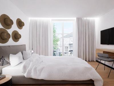 Helles Schlafzimmer mit großem Bett, Wanddeko aus Hüten und einem Schreibtisch mit Fernseher.