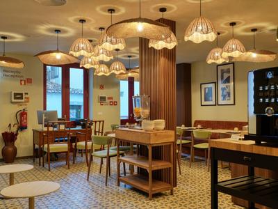 Przytulna część wypoczynkowa hotelu z drewnianymi krzesłami, lampami i stacją kawy.