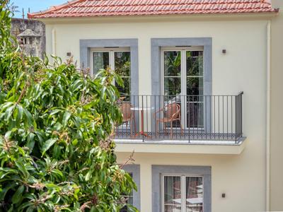 Balkon z krzesłami przy jasnym budynku obok zielonych drzew w słoneczny dzień