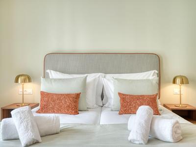 Jasno urządzony pokój hotelowy z czystym łóżkiem, poduszkami i miękkimi ręcznikami na nim.