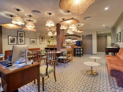 Przytulny salon hotelowy z miejscami do siedzenia, wykładziną i miękkim oświetleniem.