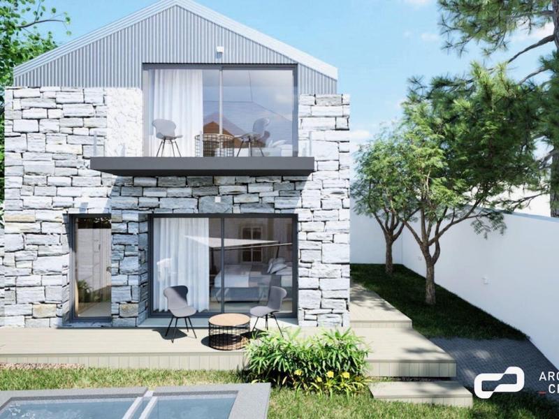 Modernes Haus mit Steinfassade, großem Balkon und gepflegtem Garten an sonnigem Tag