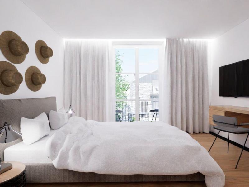 Helles Schlafzimmer mit großem Bett, Wanddeko aus Hüten und einem Schreibtisch mit Fernseher.