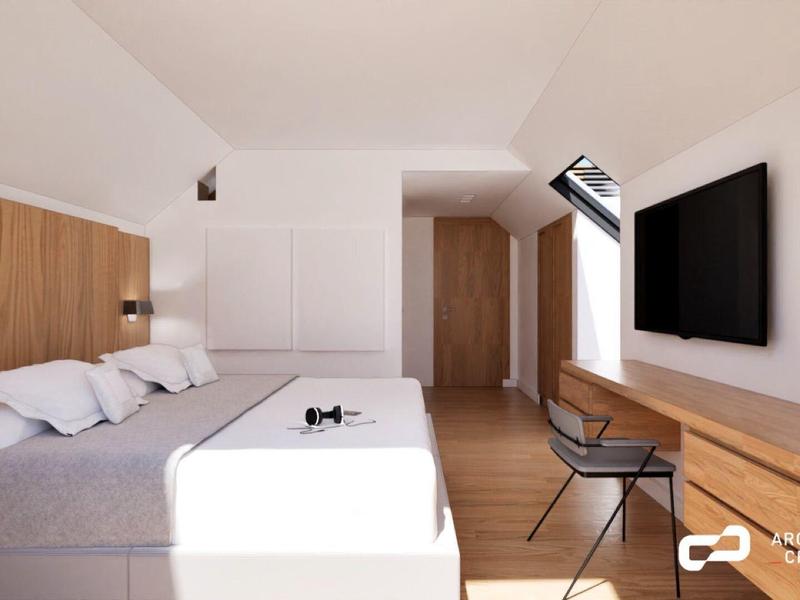 Modernes Hotelzimmer mit großem Bett, Wand-TV und Fenster im Dachgeschoss