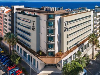 Edificio de hotel moderno en una ciudad costera con estacionamiento y calles.