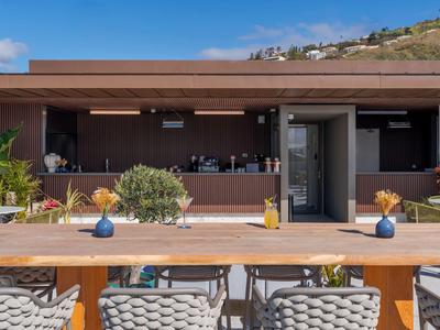 Área de hotel moderna con terraza de madera, asientos y vista a la montaña al fondo.