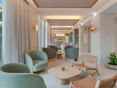 Área de espera moderna con asientos y grandes ventanas en un hotel.
