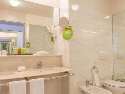 Helles Badezimmer mit großem Spiegel, Waschbecken, Handtüchern, WC und Bidet in cremefarbenem Design.