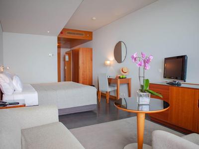 Modernes Hotelzimmer mit Doppelbett, Holzmöbeln, Tisch, Stuhl und einer pinken Orchidee.