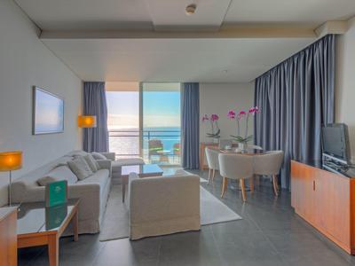 Modern eingerichtetes Wohnzimmer mit grauem Sofa, großem Fenster und Meerblick.