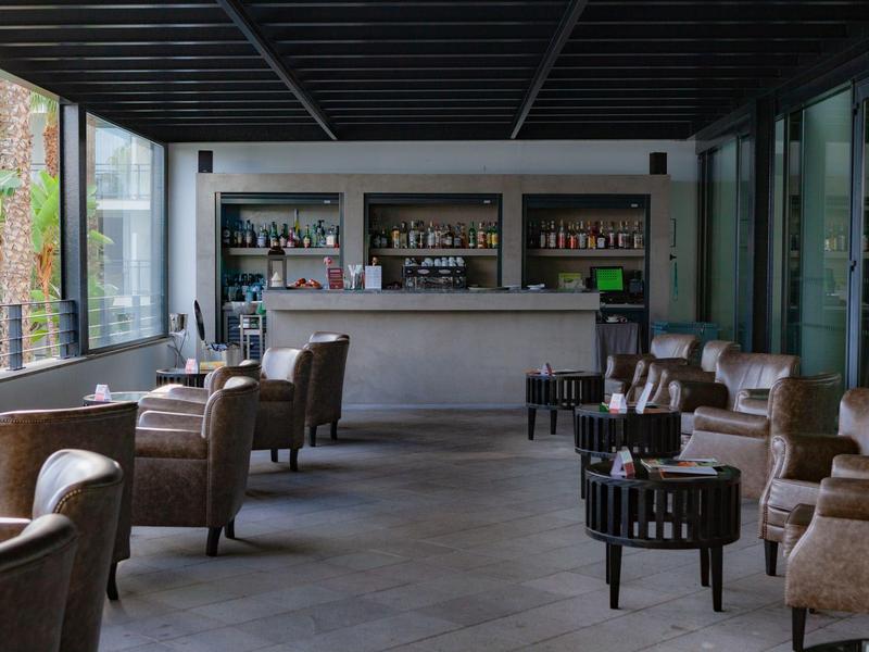 Area lounge moderna con poltrone e bar in una stanza luminosa e spaziosa.