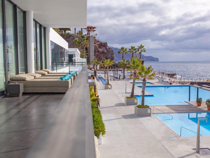 Area piscina moderna dell'hotel con vista sul mare e terrazza con divani.