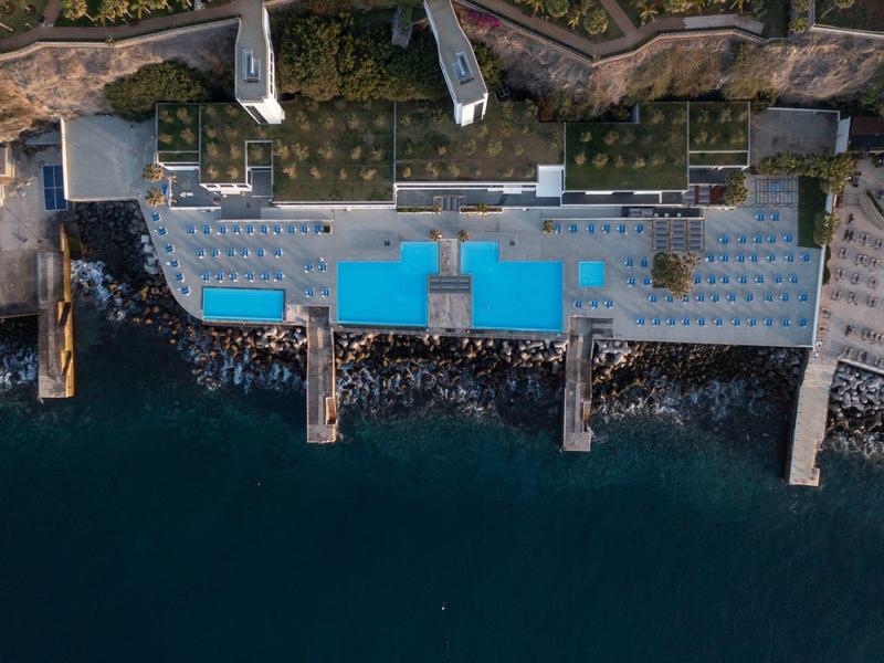 Vista aerea di un hotel con piscine vicino al mare e moli.