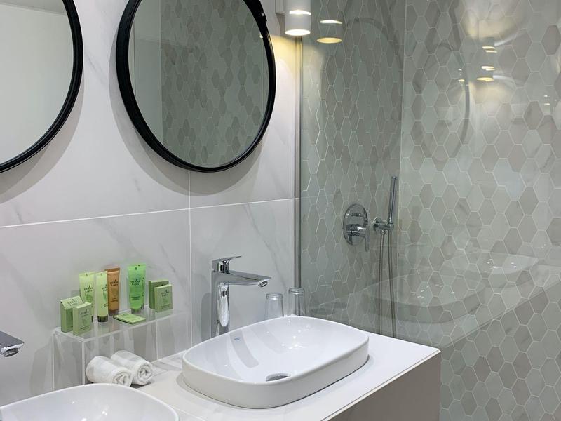 Bagno moderno con due lavandini, grandi specchi e doccia a filo pavimento.