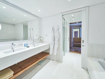 Helles, modernes Badezimmer mit langem Waschtisch, Spiegel, weißen Wänden und Holzboden-Elementen.