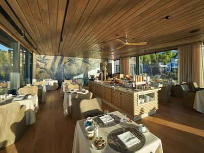 Nowoczesna restauracja z drewnianymi meblami i panoramicznymi oknami z widokiem na zieleń