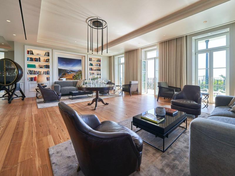 Großzügiges Wohnzimmer mit hellen Holzböden, modernen Möbeln und großen Fenstern mit Blick ins Freie.